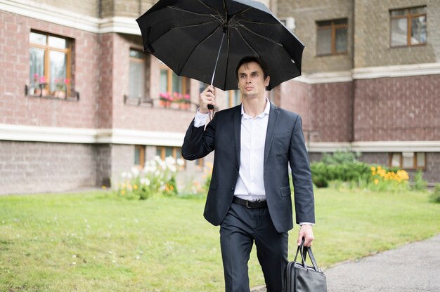 Front view of businessman holding umbrella