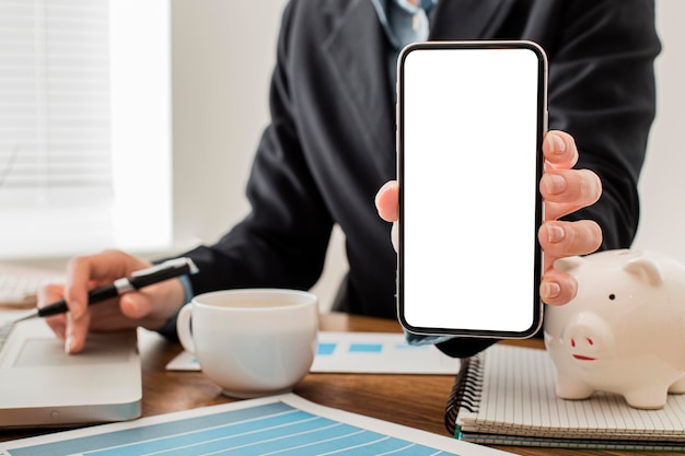 Free photo front view of businessman at the office holding blank smartphone