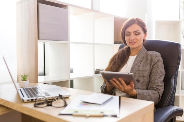 Front view of businesswoman at desk working on tablet