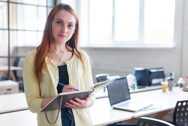 Free photo front view of businesswoman holding notebook and pen looking at camera