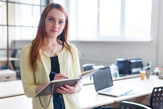 Front view of businesswoman holding notebook and pen looking at camera