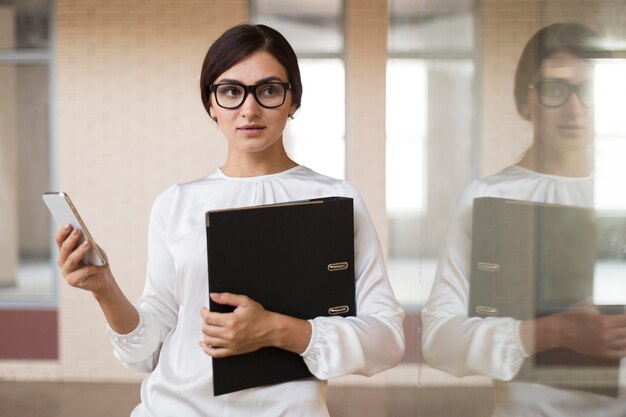 Front view of businesswoman holding smartphone and binder