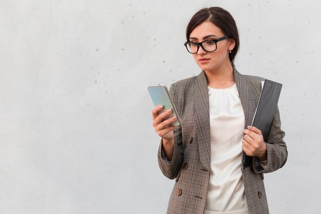 Front view of businesswoman outdoors with smartphone and notepad