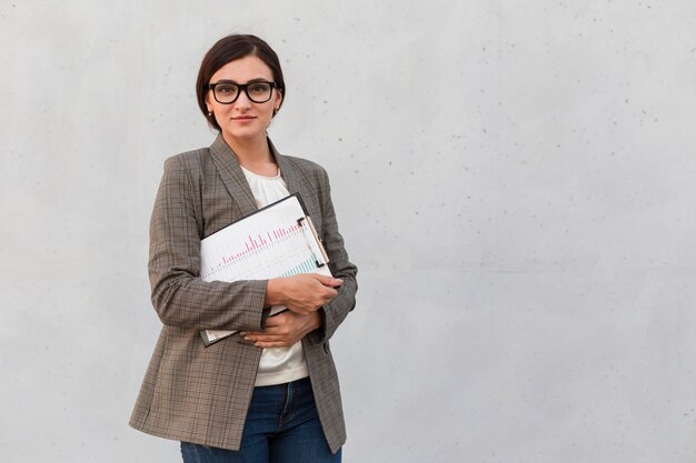 Front view of businesswoman posing outdoors with notepad