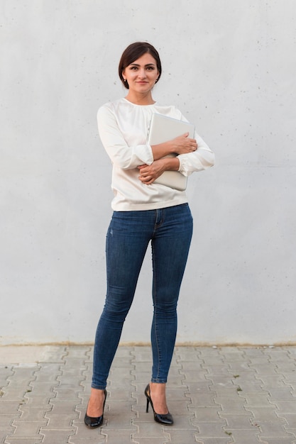 Front view of businesswoman posing outdoors with tablet