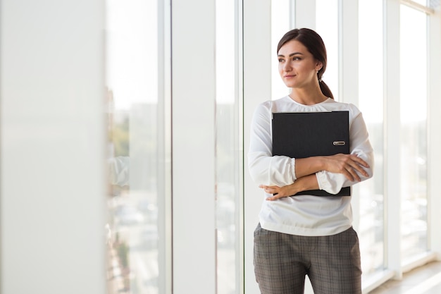 Vista frontale della donna di affari che propone mentre si tiene il legante