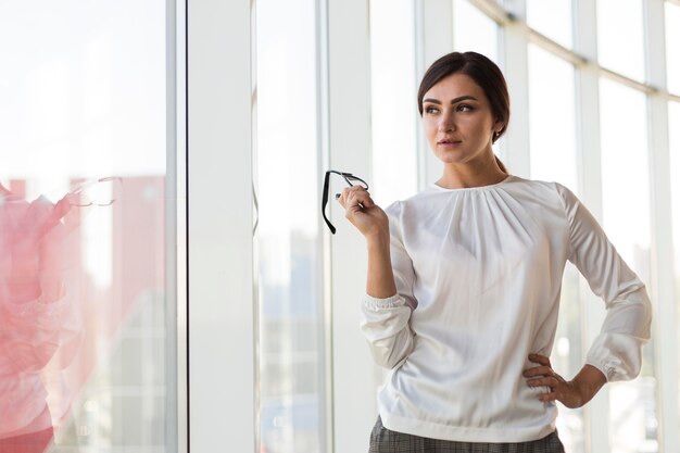 Vista frontale della donna di affari che propone con gli occhiali