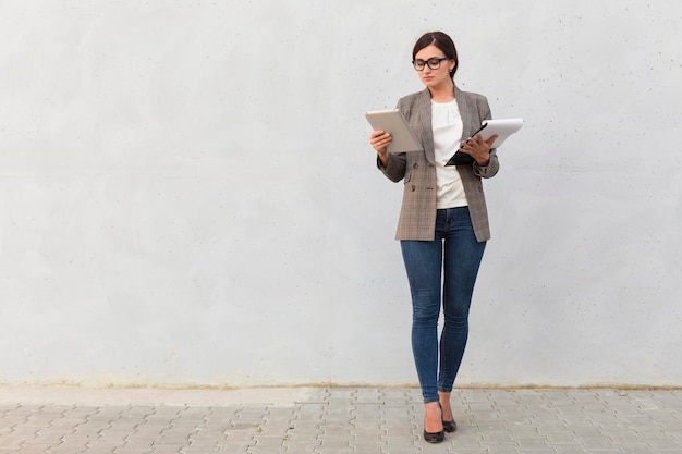 Front view of businesswoman with notepad and tablet outdoors