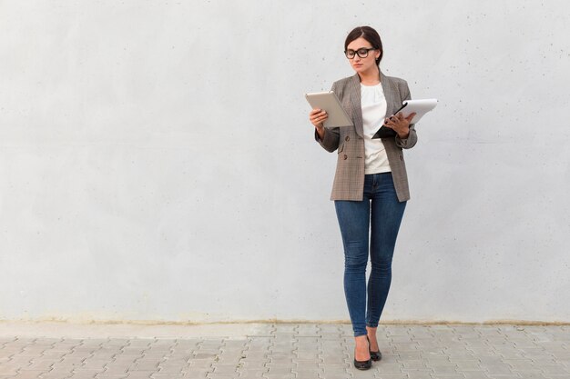 Front view of businesswoman with notepad and tablet outdoors