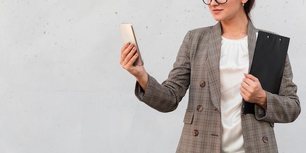 Foto gratuita vista frontale della donna di affari con lo smartphone e il blocco note all'esterno