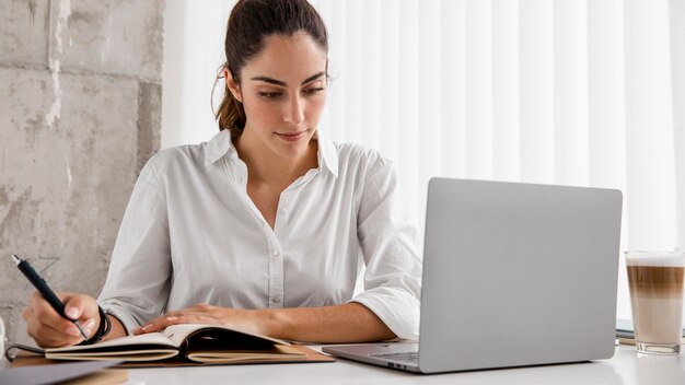 Вид спереди деловой женщины, работающей с ноутбуком и ноутбуком
