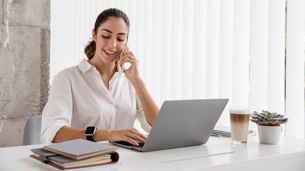 Вид спереди деловой женщины, работающей со смартфоном и ноутбуком