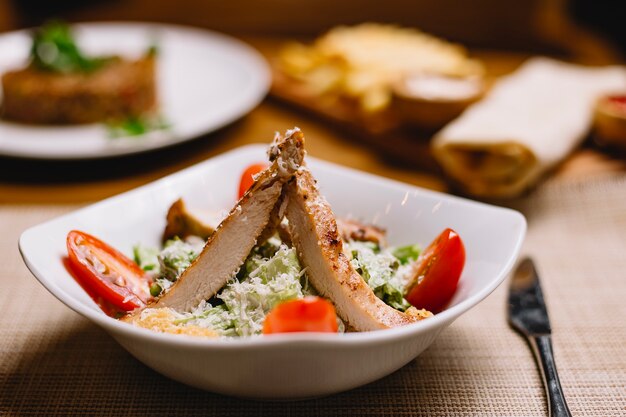 Front view caesar salad with chicken and tomato slices