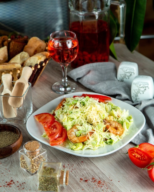 Бесплатное фото Салат «цезарь» с ломтиками томатов и креветками, безалкогольный напиток.