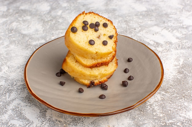 Front view of cake slice inside plate with choco chips on the light desk