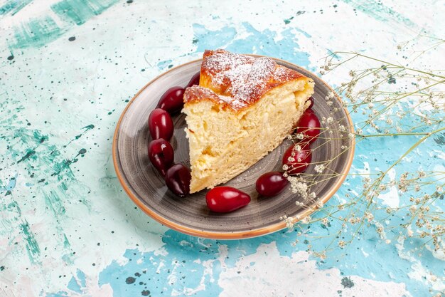 Front view cake slice wit fresh red dogwoods on blue desk