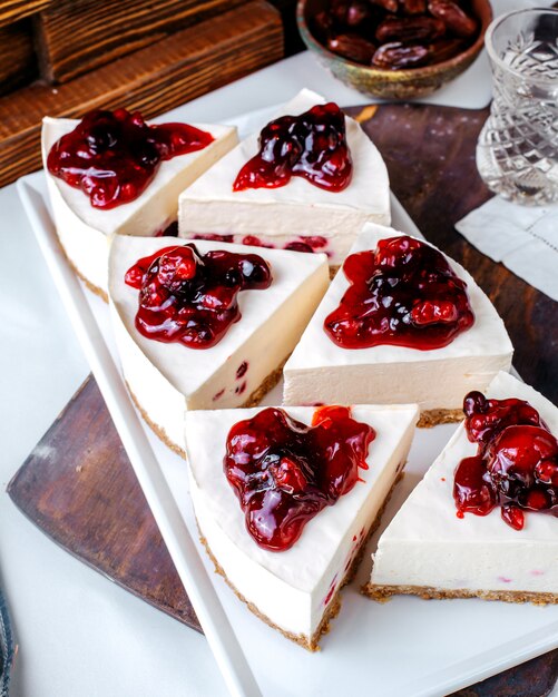 Вид спереди кусочки торта вишневого куска внутри белой тарелке на светлой поверхности