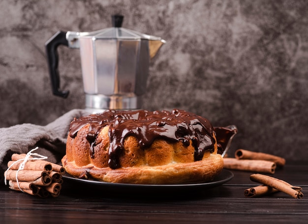 Vista frontale della torta con topping al cioccolato e bastoncini di cannella