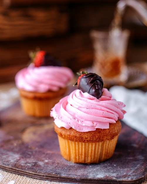 Free photo front view cakes little with brown cream and strawberry on the brown surface