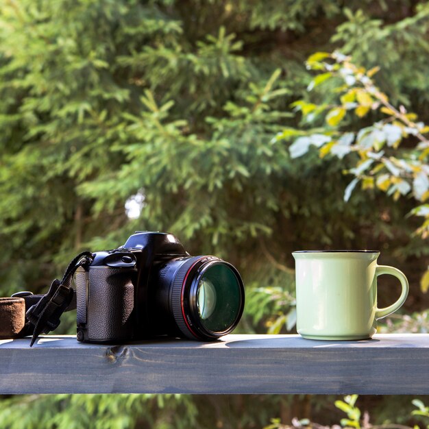 Front view camera anc cup of coffee in nature