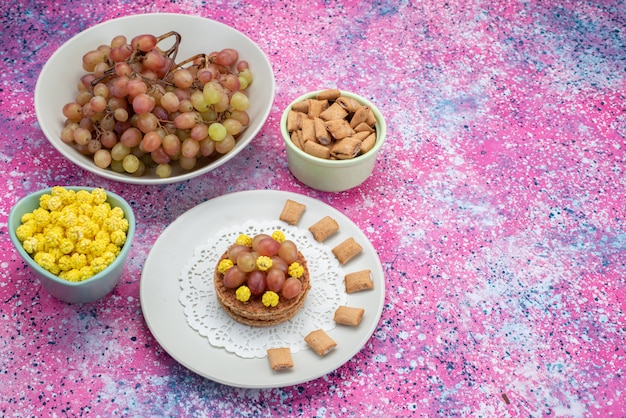 Front view of candies and grape on the colorful surface