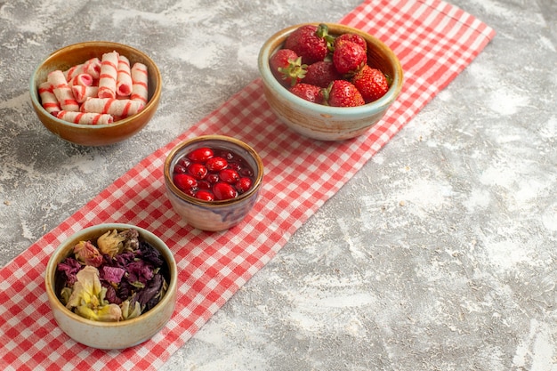 Front view candies and jelly with strawberries on white surface candy sweet flower