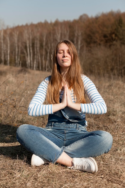 Front view of carefree woman meditating in nature