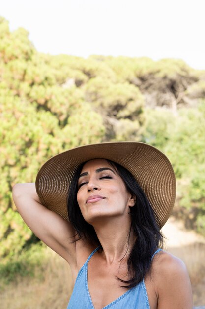 Front view of carefree woman with hat outdoors