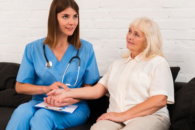 Front view caregiver holding hands with old woman