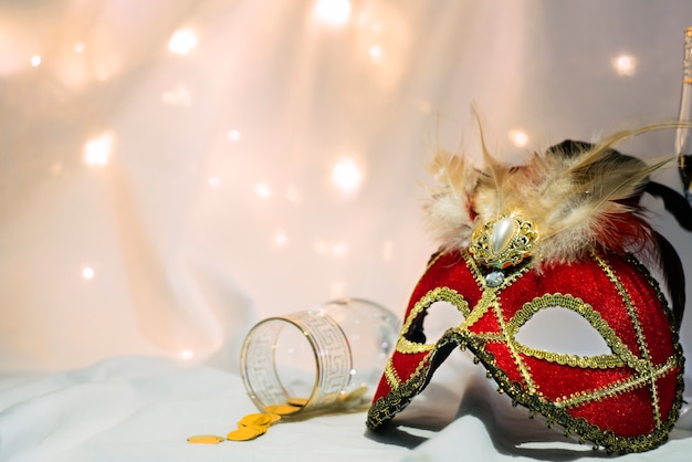 Front view of a carnival mask and a glass with coins