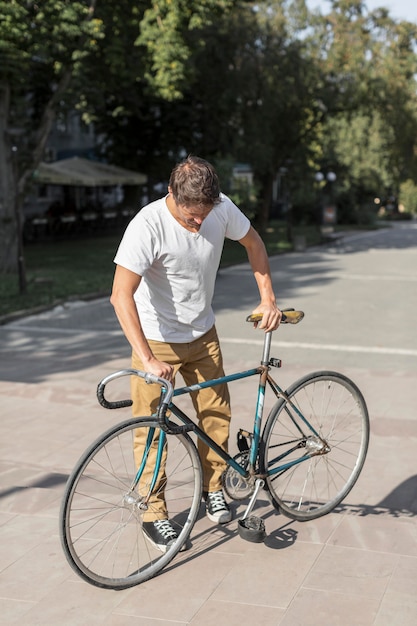 彼の自転車をチェックする正面カジュアルな男性