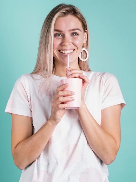 フロントビューカジュアルな女性の飲み物を飲みながら