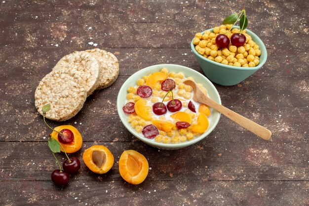 Front view cereals with milk inside plate with crackers and fruits on the brown wooden background drink milk dairy creamery