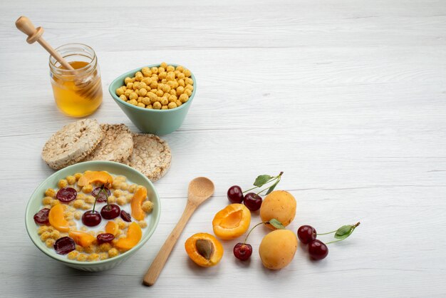 Front view cereals with milk inside plate with crackers fruits and honey on the white background drink milk dairy creamery breakfast