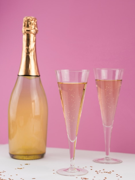 Вид спереди бутылки шампанского с наполненными бокалами