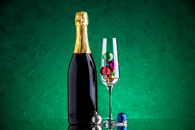 Front view champagne small xmas balls in wine glass on green surface