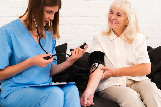 Front view checking old woman's blood pressure 