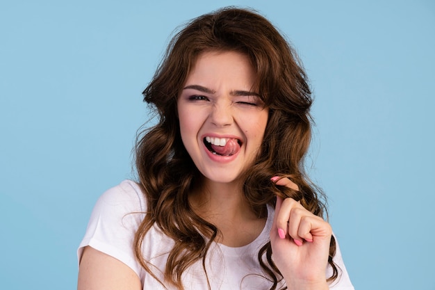 Front view of cheeky woman with tongues out touching her hair