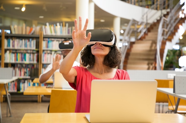 Front view of cheerful Caucasian woman wearing VR headset