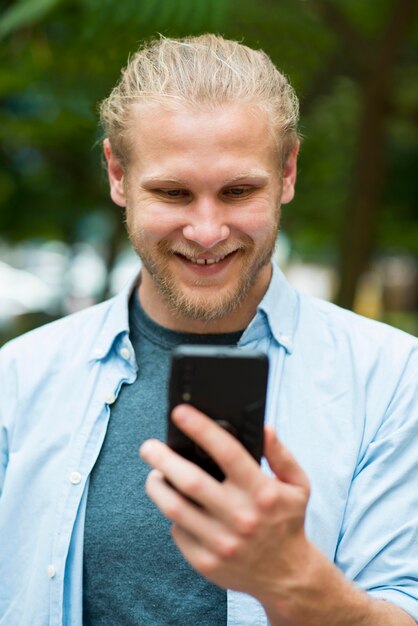 Front view of cheerful man looking at phone