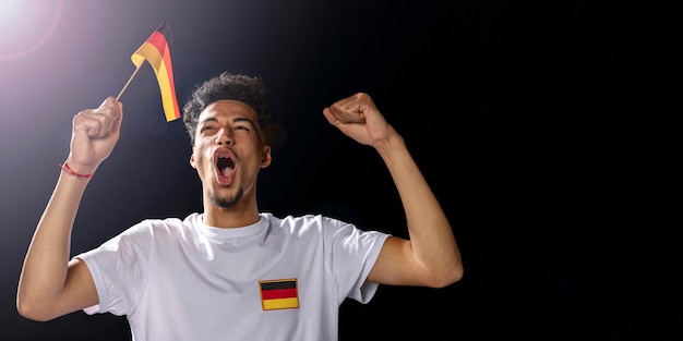 Вид спереди ликующего человека, держащего немецкий флаг