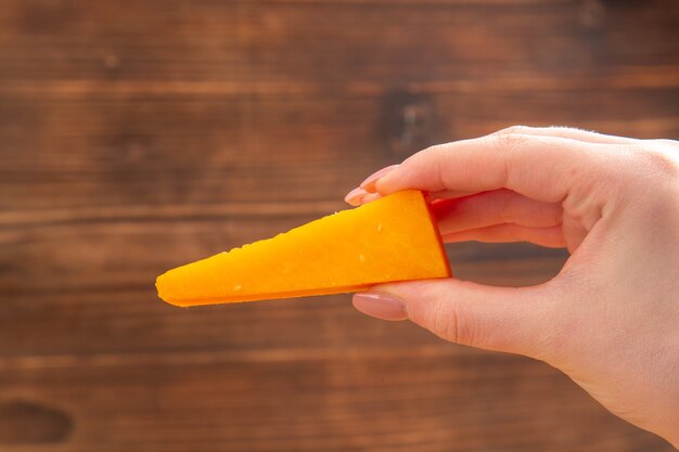 Front view cheese in female hand on brown isolated surface