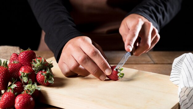 Front view of chef in apron chopping strawberries