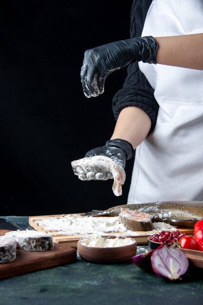 Front view chef covering fish slices with flour on kitchen table