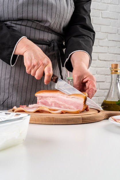 Front view of chef cutting bacon