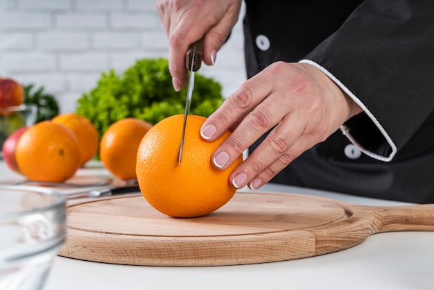 Front view of chef cutting an orange