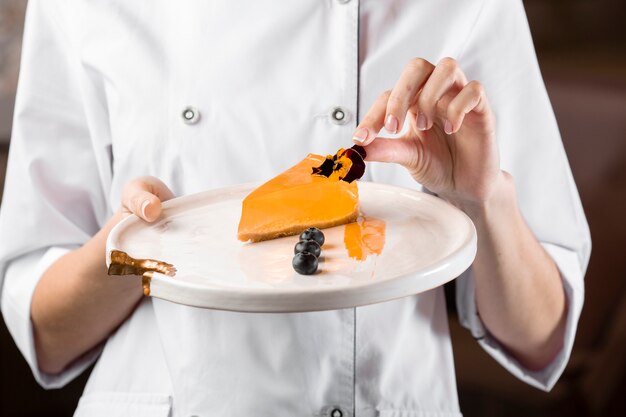 Front view of chef holding a plate with cake