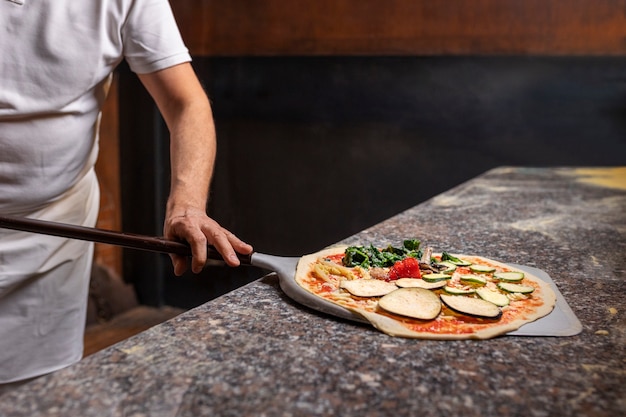 Free photo front view chef preparing pizza