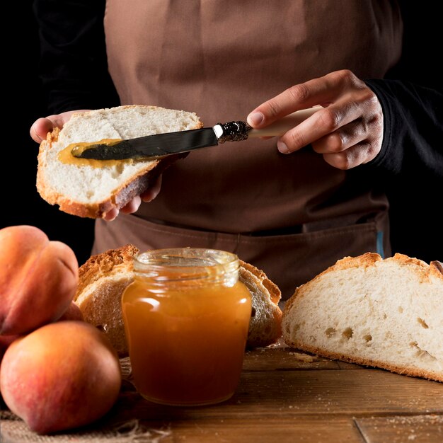 Front view of chef spreading peach marmalade on bread