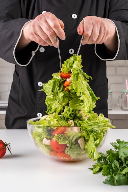 Front view of chef tossing salad